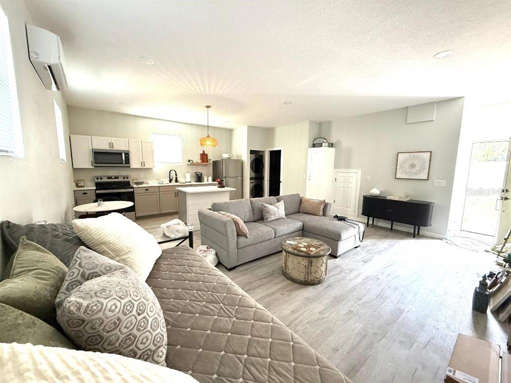 An open-concept living room and kitchen area with light wood-look flooring and gray furniture — 1183 CHESTNUT STREET UNIT B, CLERMONT, FL