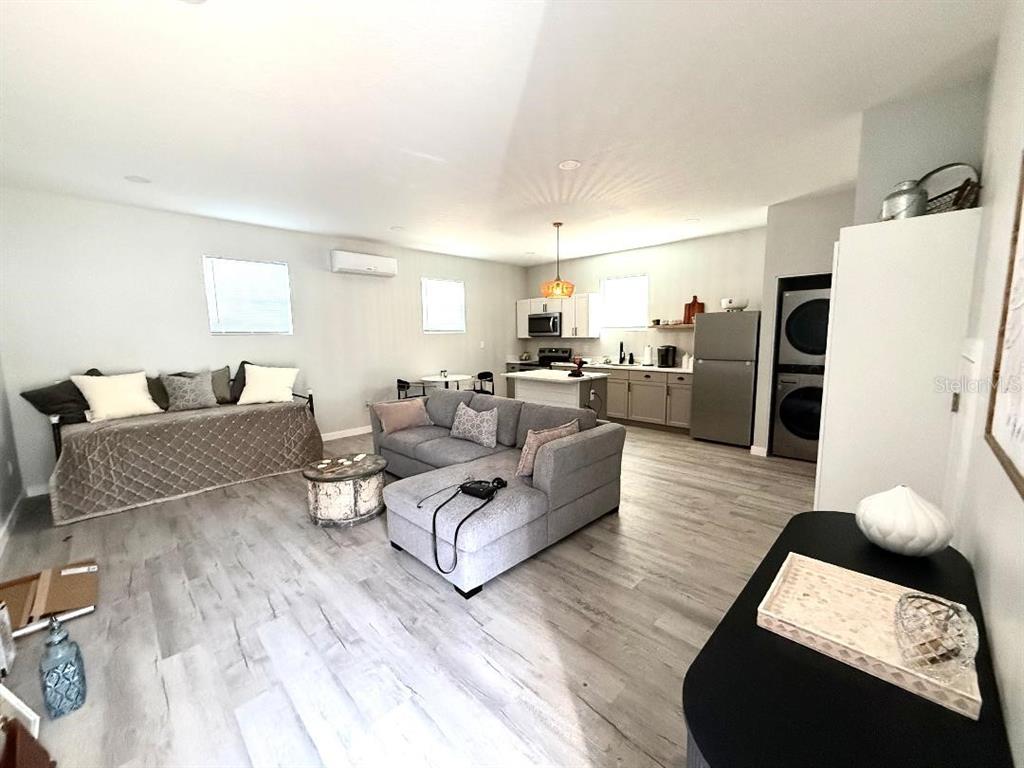 An open-concept living room and kitchen featuring gray wood-look flooring and neutral walls — 1183 CHESTNUT STREET UNIT B, CLERMONT, FL