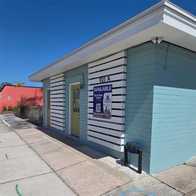 A light blue, single-story commercial building with a white slatted facade and yellow doors — 921 RIDGEWOOD AVENUE UNIT A, HOLLY HILL, FL
