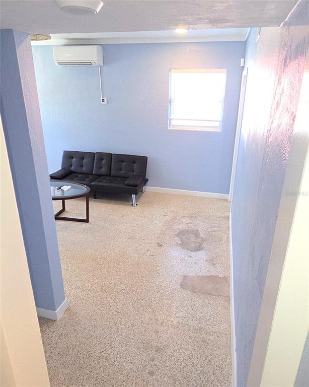 A room with light blue walls, a black sofa, a coffee table, and speckled flooring — 921 RIDGEWOOD AVENUE UNIT A, HOLLY HILL, FL