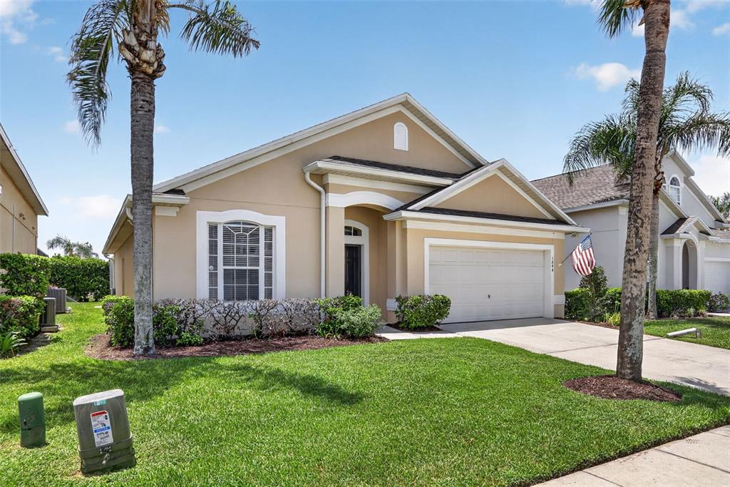 A tan single-story house with a two-car garage and palm trees in the front yard — 1844 MORNING STAR DRIVE, CLERMONT, FL