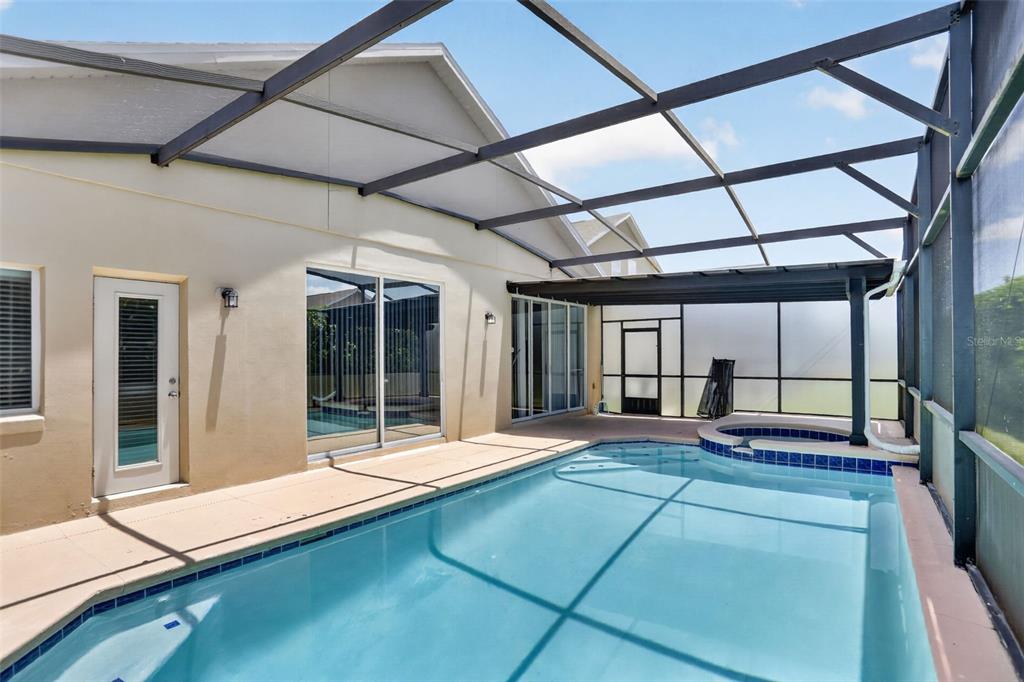 A screened-in swimming pool and attached spa sit on a patio beside a house — 1844 MORNING STAR DRIVE, CLERMONT, FL