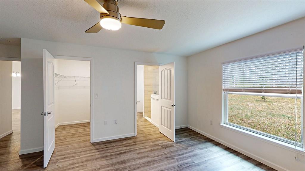 A bedroom features wood-look flooring, a ceiling fan, a walk-in closet, and an attached bathroom — 2816 TRICO ROAD, NORTH PORT, FL