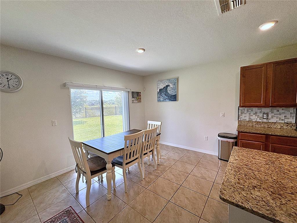 A dining area with a table, chairs, tile floors, and a sliding glass door — 1116 FOX PATH ROAD, DAVENPORT, FL