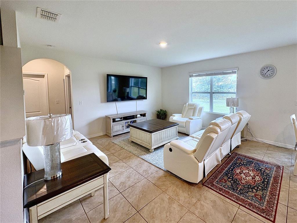 A living room features white leather furniture, a television, and tile flooring — 1116 FOX PATH ROAD, DAVENPORT, FL