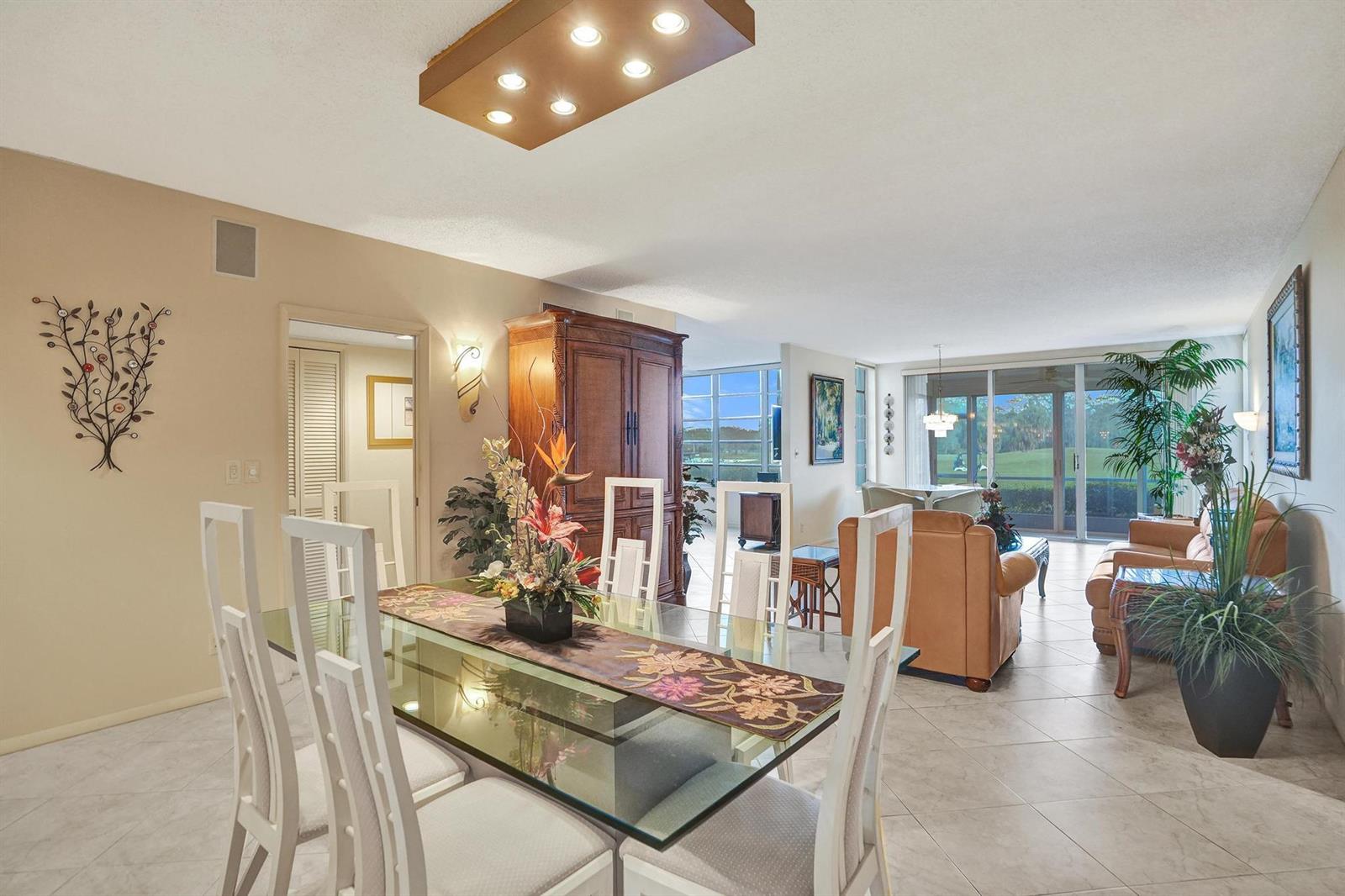 A dining area with a glass table opens into a living room with golf course views — 806 Cypress Boulevard # 104, Pompano Beach FL 33069, POMPANO BEACH, FL