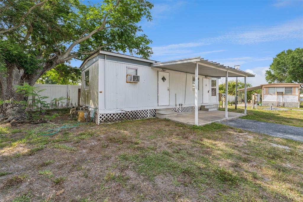 A white mobile home with a covered porch and metal roof sits on a grassy lot — 2854 LAKE ALFRED UNIT 6, WINTER HAVEN, FL