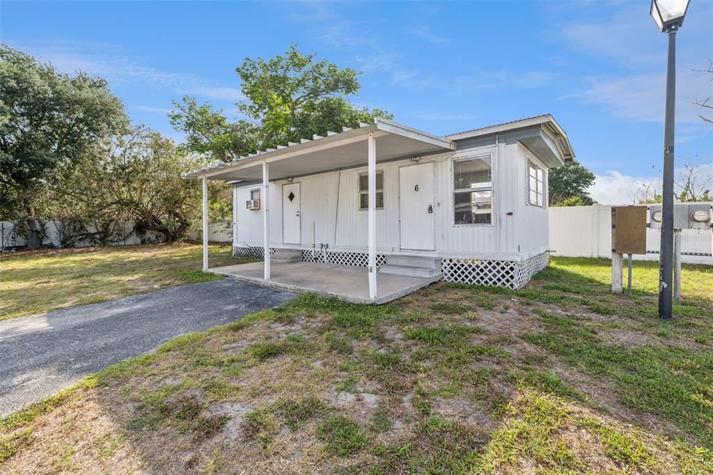 A white mobile home with a covered carport and lattice skirting sits on a grassy lot — 2854 LAKE ALFRED UNIT 6, WINTER HAVEN, FL