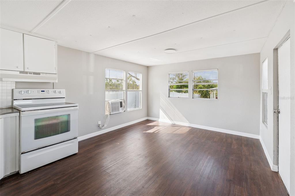 A kitchen area features white cabinets, a white stove, and dark wood-look flooring — 2854 LAKE ALFRED UNIT 6, WINTER HAVEN, FL