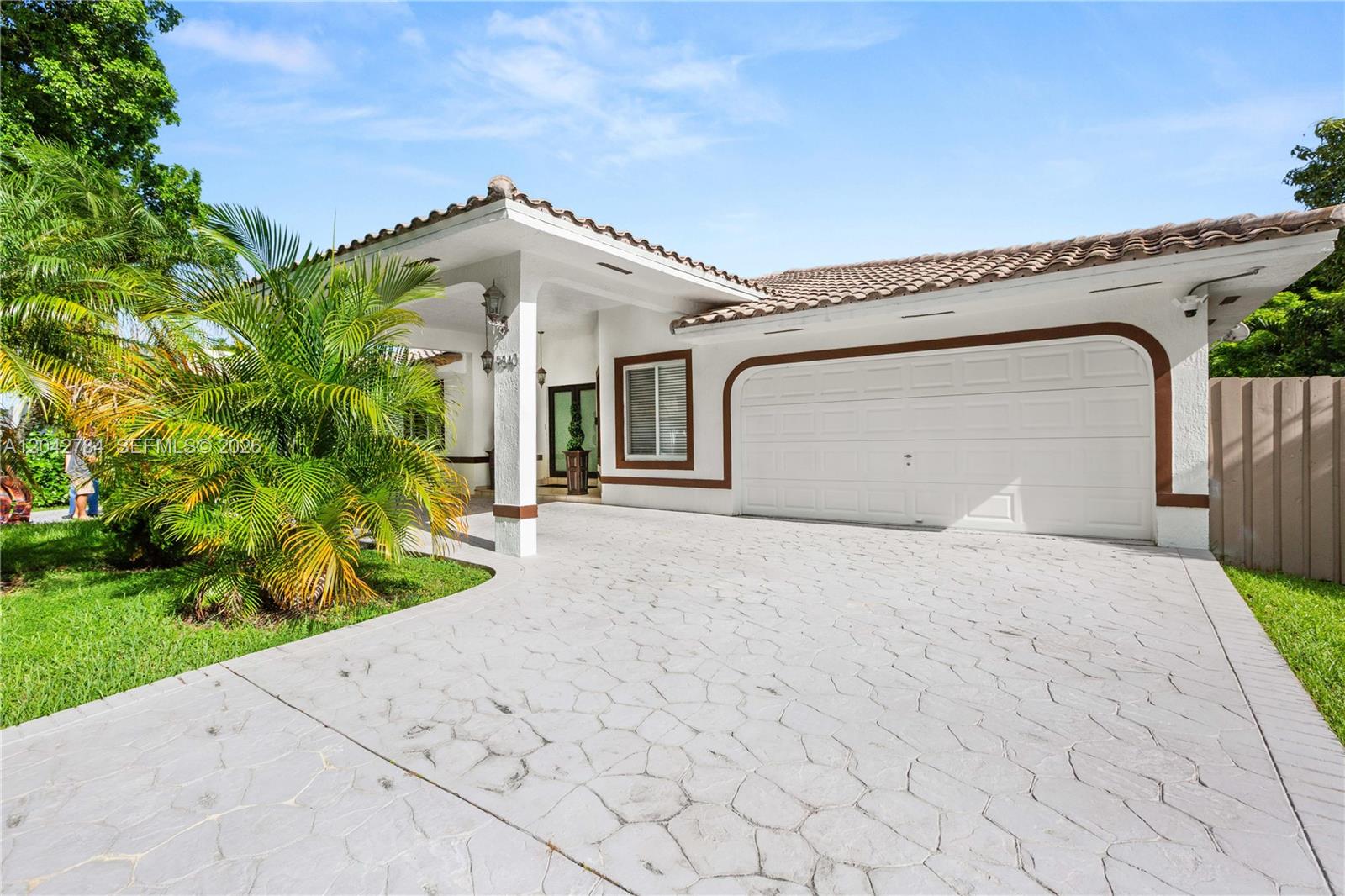 A single-story house with a white stucco facade, tiled roof, and a stamped concrete driveway — 9840 NW 28th Ter, Doral FL 33172, DORAL, FL