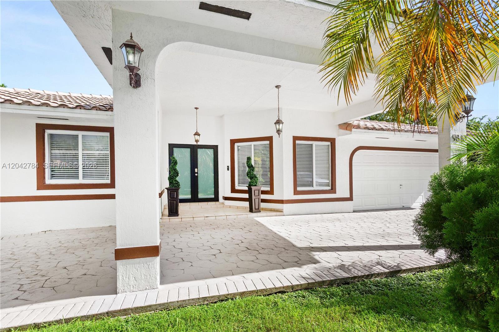 The exterior of a white house features a covered entryway, a garage, and a paved driveway — 9840 NW 28th Ter, Doral FL 33172, DORAL, FL