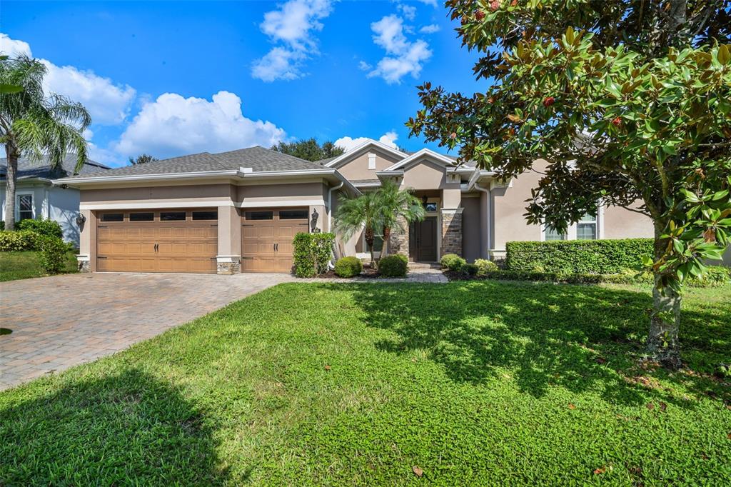 A single-story house with a two-car garage, stone accents, and a paved driveway — 410 SAUVIGNON WAY, GROVELAND, FL