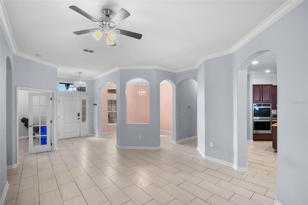 A bright, open-concept living area features light-colored tile flooring, arched entryways, and a ceiling fan — 410 SAUVIGNON WAY, GROVELAND, FL