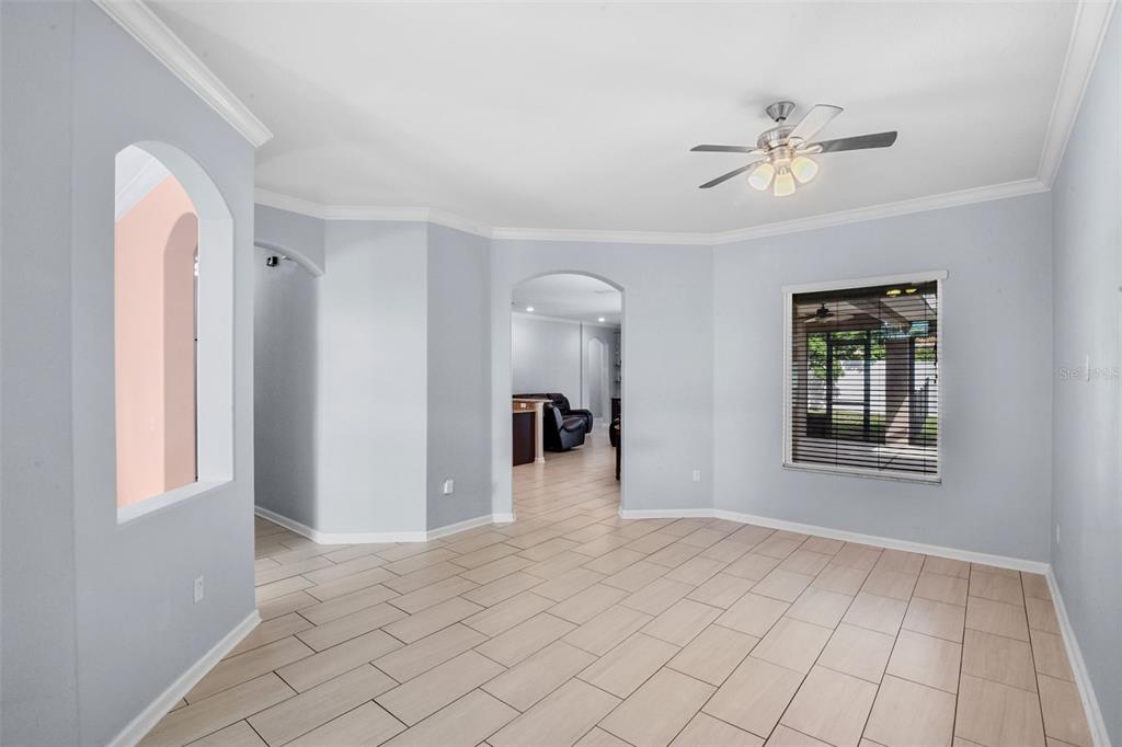 An empty room with light blue walls, tile flooring, an arched doorway, and a ceiling fan — 410 SAUVIGNON WAY, GROVELAND, FL