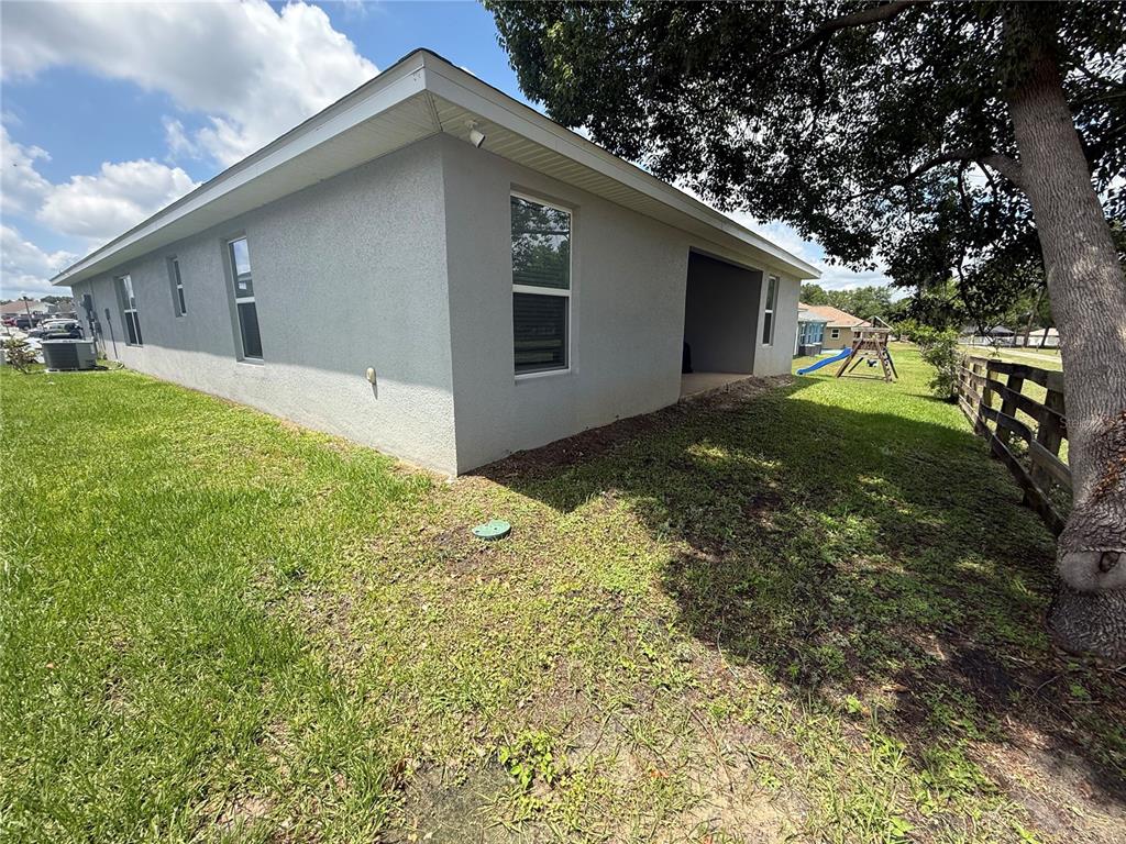 The exterior side of a gray stucco house features several windows and a covered patio — 199 NW 45TH LOOP, OCALA, FL