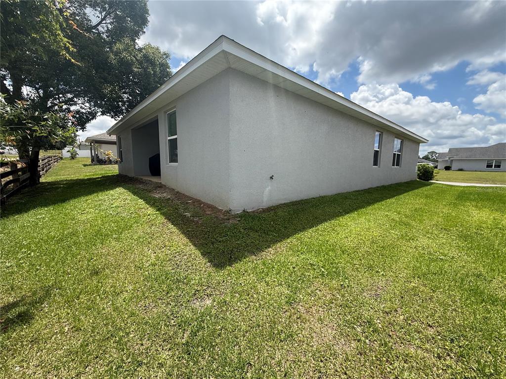A view of the side and back exterior of a gray stucco house with windows — 199 NW 45TH LOOP, OCALA, FL