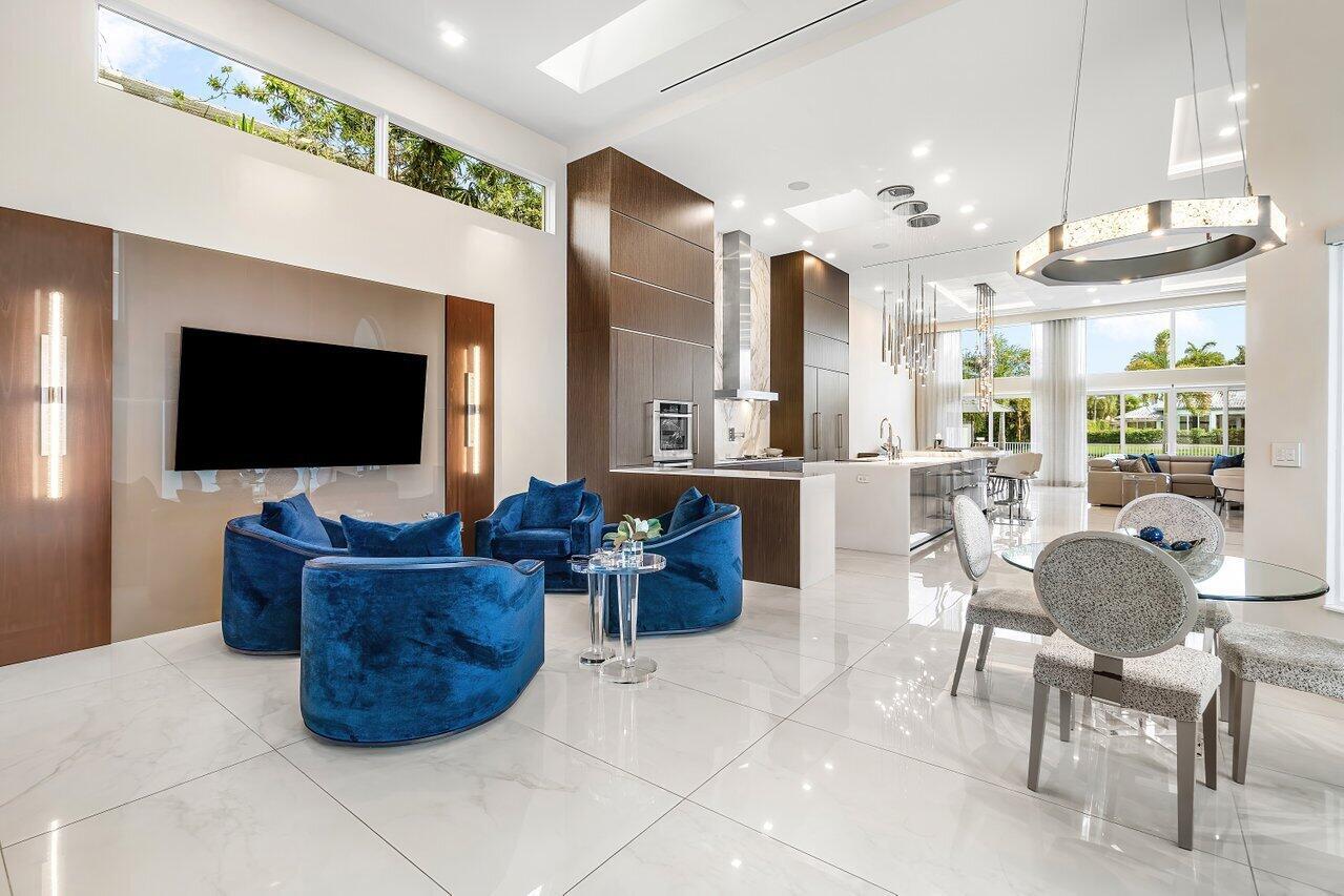 A modern open-concept living and dining area features blue velvet chairs and white marble floors — 3506 NW Clubside Circle, Boca Raton FL 33496, BOCA RATON, FL