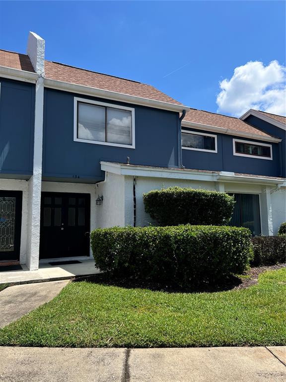 A two-story townhouse features blue siding, white stucco, and a dark front door — 134 LAGO VISTA BOULEVARD, CASSELBERRY, FL