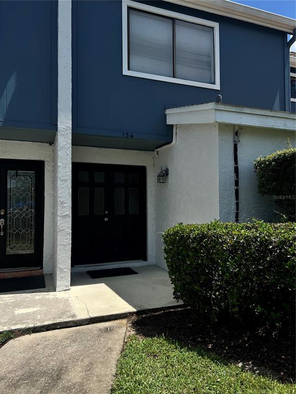 A two-story building exterior features a dark blue upper level, white stucco walls, and double doors — 134 LAGO VISTA BOULEVARD, CASSELBERRY, FL