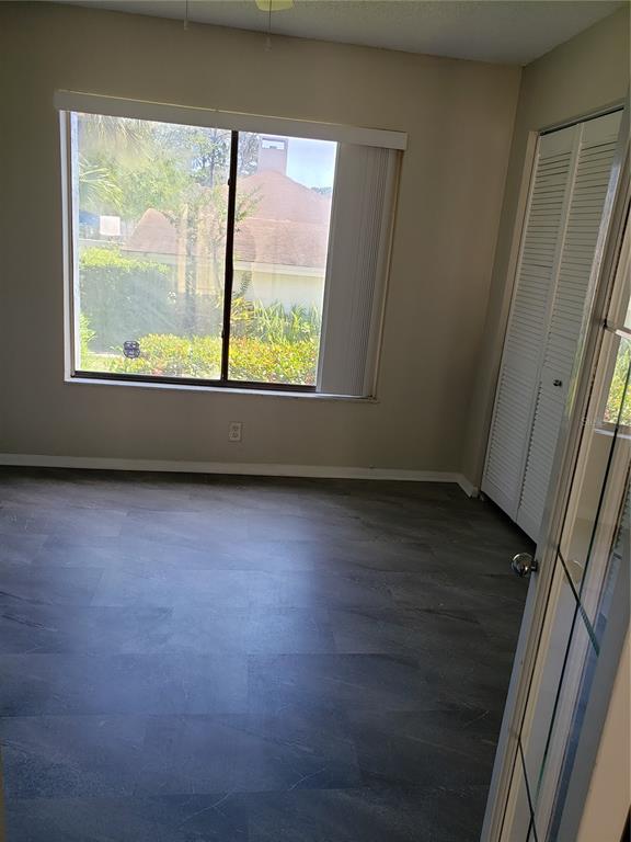 An empty room with gray tile flooring, a large window, and white louvered closet doors — 134 LAGO VISTA BOULEVARD, CASSELBERRY, FL