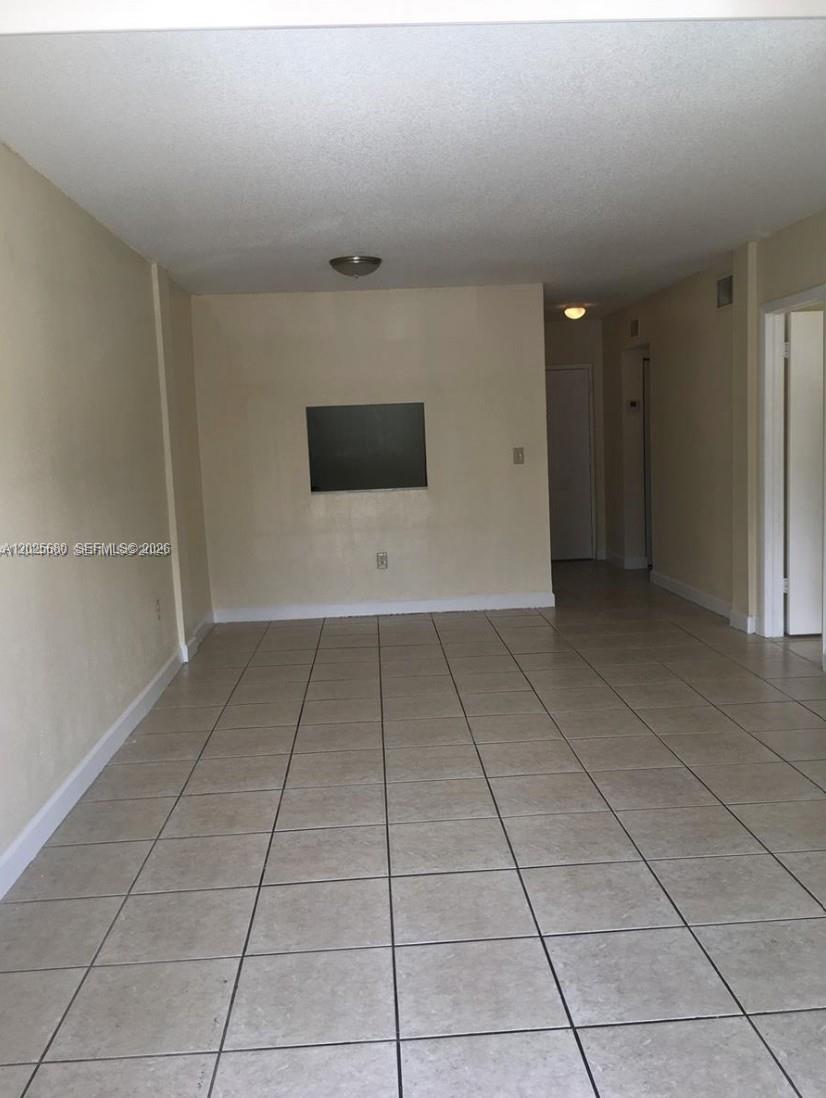 A kitchen with white cabinets and a marble-look countertop is viewed through a pass-through window — 10900 SW 104th St # 210, Miami FL 33176, MIAMI, FL