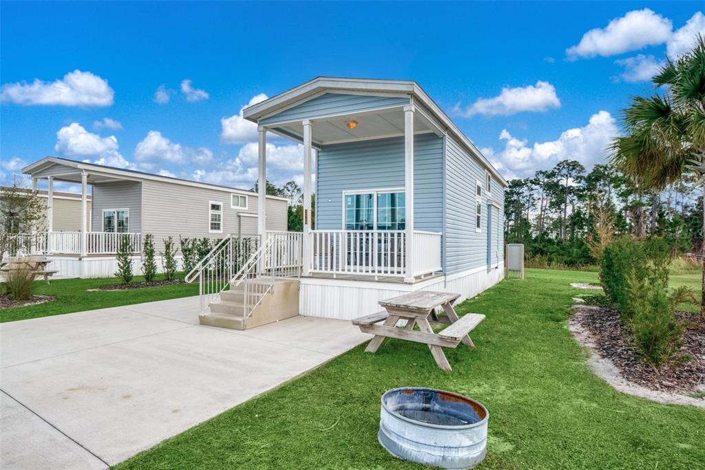 A light blue tiny home with a front porch and picnic table sits on grass — 0 HIGHWAY 630 E UNIT 329, LAKE WALES, FL