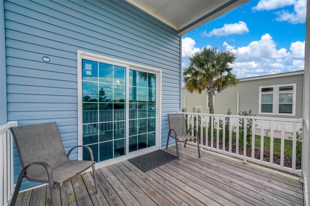 A wooden deck with two chairs sits outside a blue house with sliding glass doors — 0 HIGHWAY 630 E UNIT 329, LAKE WALES, FL