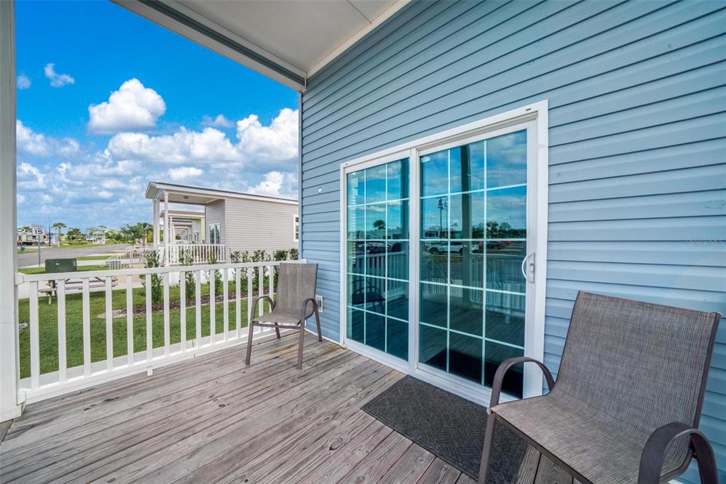 A wooden deck with two chairs sits outside a blue house with sliding glass doors — 0 HIGHWAY 630 E UNIT 329, LAKE WALES, FL