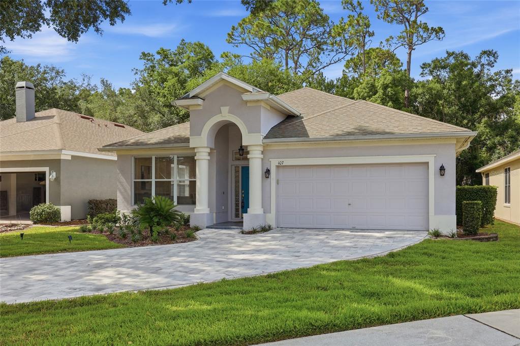 A single-story house with a beige stucco exterior, a two-car garage, and a paved driveway — 107 GOLDEN CREST COURT, WINTER SPRINGS, FL