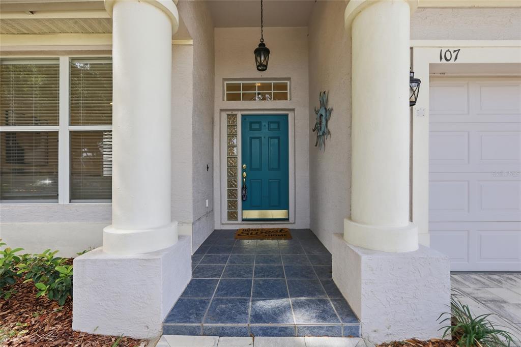 The front entrance features a teal door, tiled porch, and two large white columns — 107 GOLDEN CREST COURT, WINTER SPRINGS, FL