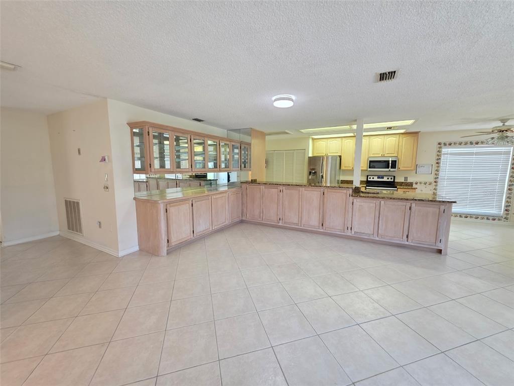 A kitchen with light wood cabinets, tile flooring, and a large peninsula counter — 2376 BENT PINE COURT, SPRING HILL, FL