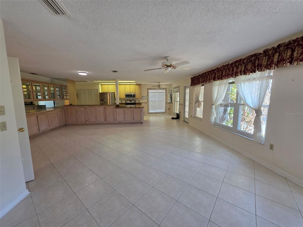 A spacious living area with tile flooring, a kitchen with wood cabinets, and large windows — 2376 BENT PINE COURT, SPRING HILL, FL