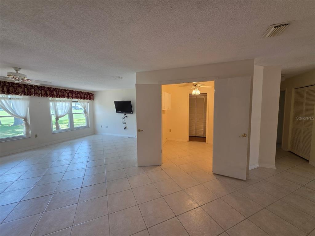 A living room with tile flooring features a television mounted on the wall — 2376 BENT PINE COURT, SPRING HILL, FL