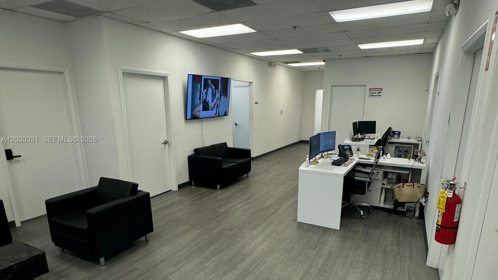 An office reception area features a white desk, black seating, and a wall-mounted television — 10133 USA TODAY WAY, Miramar FL 33025, MIRAMAR, FL