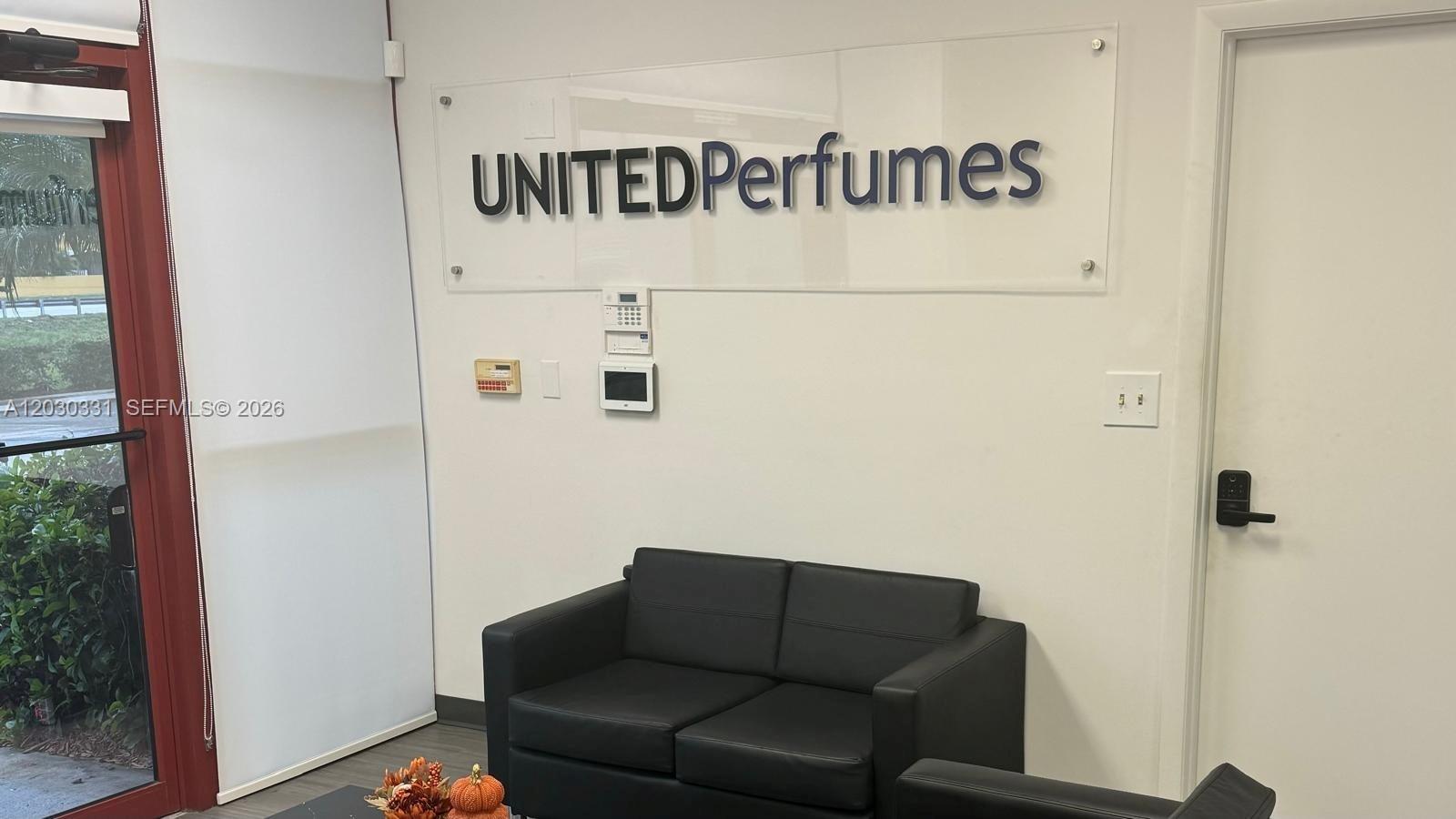 A waiting area features a black sofa, a wall-mounted company sign, and a glass door — 10133 USA TODAY WAY, Miramar FL 33025, MIRAMAR, FL