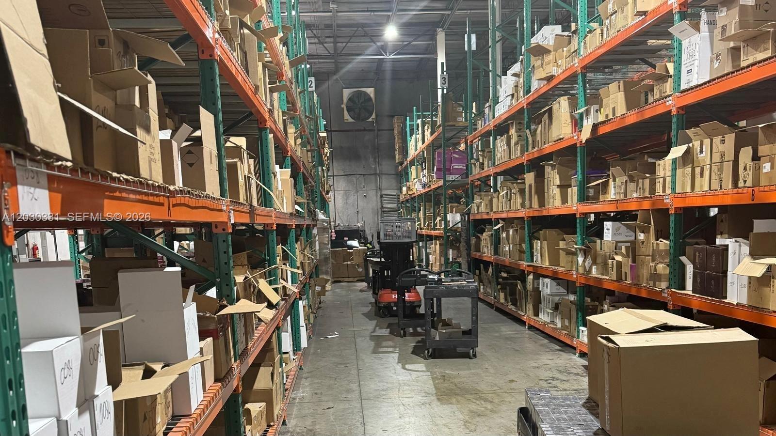 A warehouse aisle features tall metal shelving units filled with numerous cardboard boxes — 10133 USA TODAY WAY, Miramar FL 33025, MIRAMAR, FL