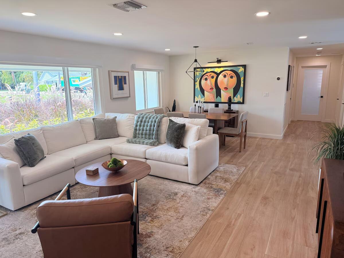 A bright living and dining area features a white sectional sofa, wood flooring, and artwork — 541 Ibis Drive, Delray Beach FL 33444, DELRAY BEACH, FL