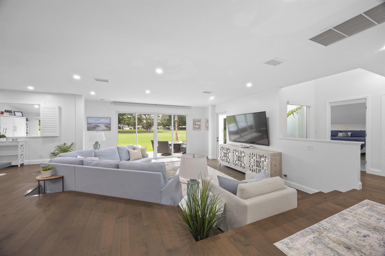 A sunken living room features a sectional sofa, a television console, and sliding glass doors — 17235 Bay Street, Jupiter FL 33477, JUPITER, FL