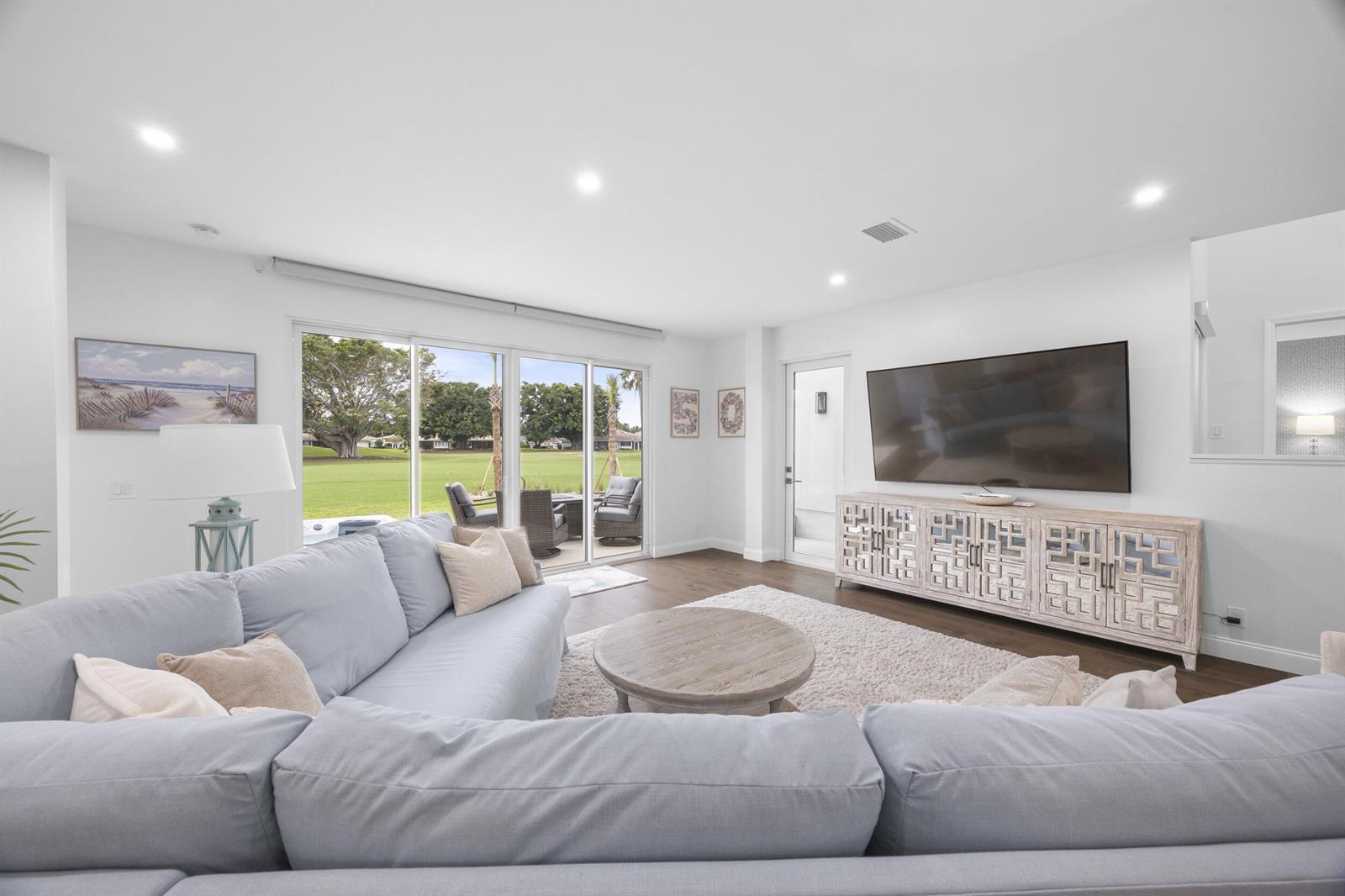 A living room features a light blue sectional sofa, a round wooden table, and sliding doors — 17235 Bay Street, Jupiter FL 33477, JUPITER, FL