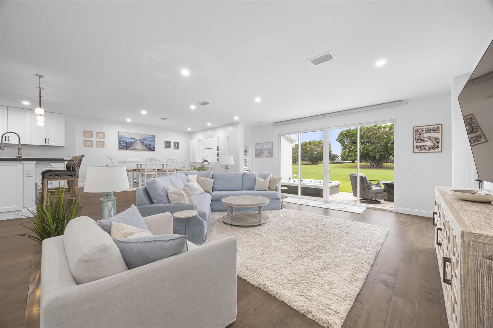 A bright living room features a blue sectional, white rug, and sliding doors to a patio — 17235 Bay Street, Jupiter FL 33477, JUPITER, FL