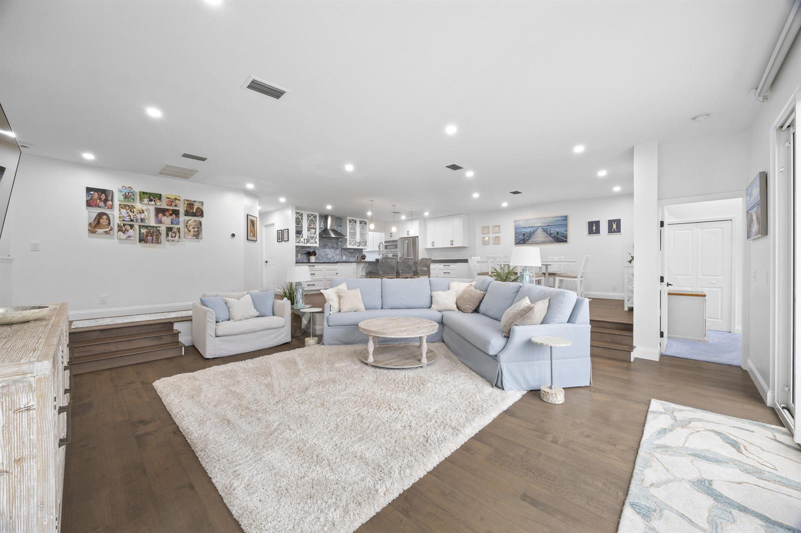 An open-concept living room features a light blue sectional, a white rug, and hardwood floors — 17235 Bay Street, Jupiter FL 33477, JUPITER, FL