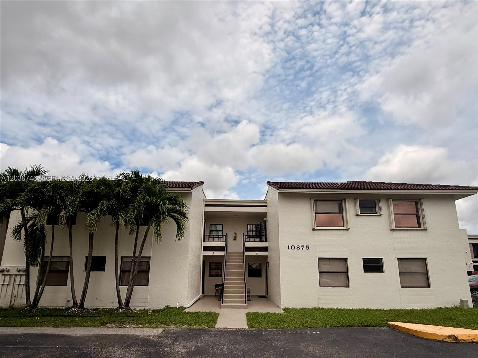 A two-story apartment building with a central staircase and palm trees in front — 10875 NW 7th St # 36, Miami FL 33172, MIAMI, FL