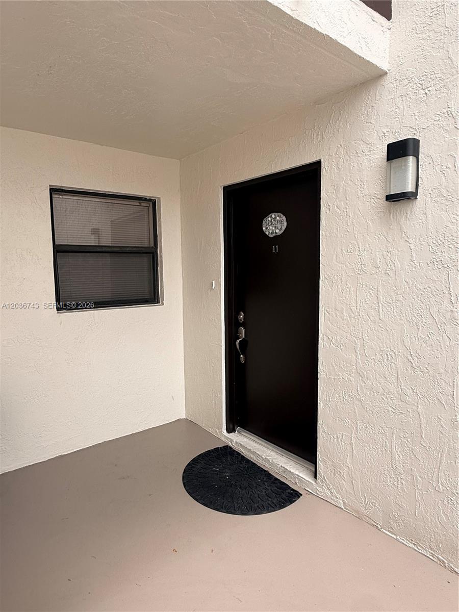 This is an exterior view of a residential entryway with a black door and window — 10875 NW 7th St # 36, Miami FL 33172, MIAMI, FL