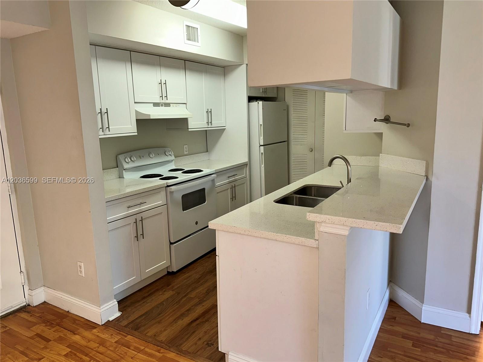 A kitchen features white cabinets, white appliances, and a peninsula with a double sink — 460 S Park Rd # 203, Hollywood FL 33021, HOLLYWOOD, FL