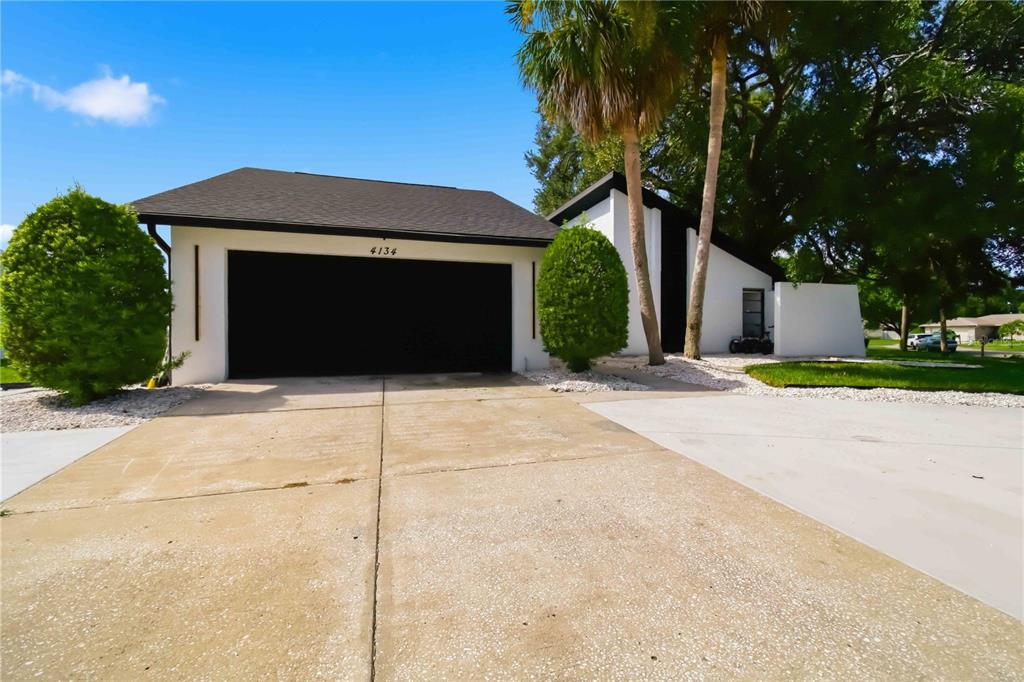 A modern white house with a black garage door and a concrete driveway — 4134 EASTWOOD DRIVE, SARASOTA, FL