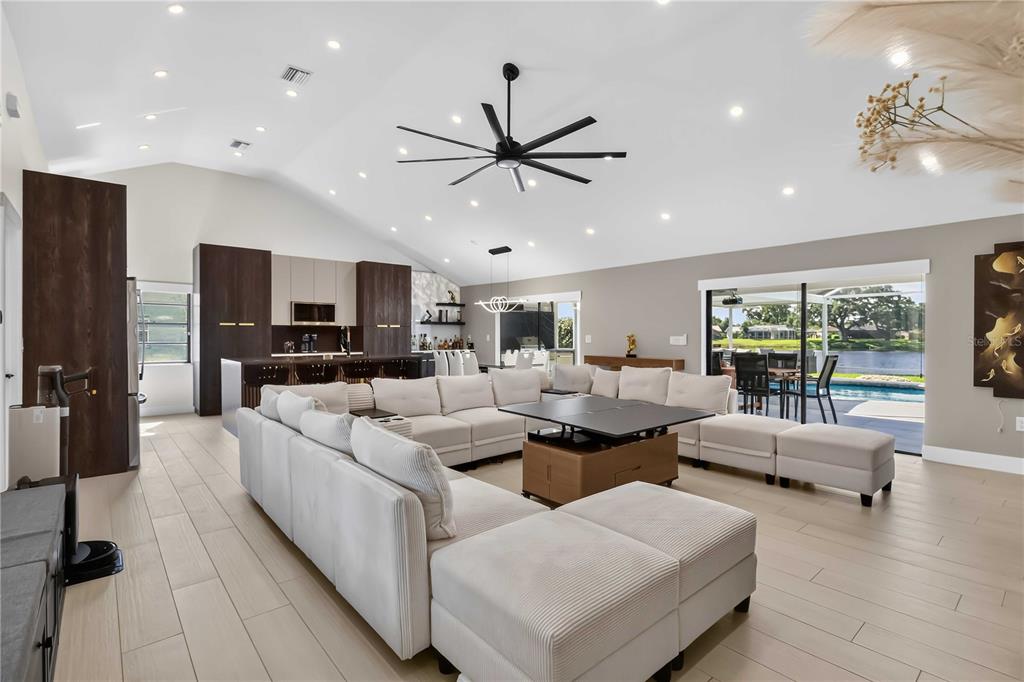 A spacious open-concept living room features a large sectional sofa, vaulted ceilings, and kitchen area — 4134 EASTWOOD DRIVE, SARASOTA, FL