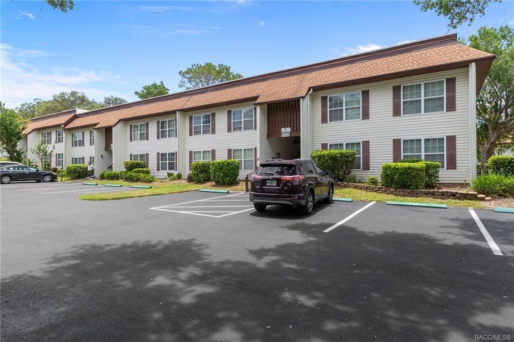 A two-story apartment building with beige siding and a brown shingled roof faces a parking lot — 2400 FOREST DRIVE UNIT 243, INVERNESS, FL