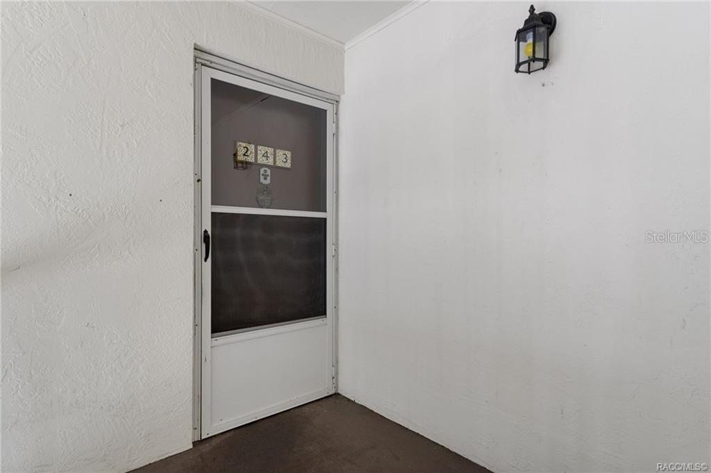 A white exterior door with a screen and the number 243 is set in a wall — 2400 FOREST DRIVE UNIT 243, INVERNESS, FL
