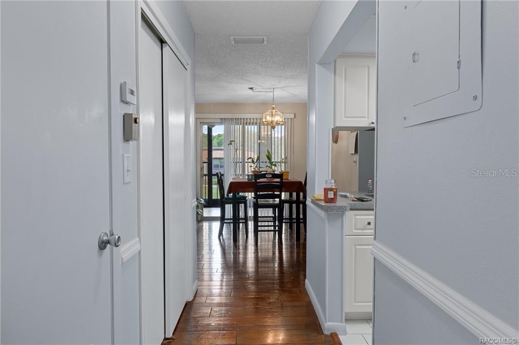 A hallway with hardwood floors leads to a dining area with a sliding glass door — 2400 FOREST DRIVE UNIT 243, INVERNESS, FL