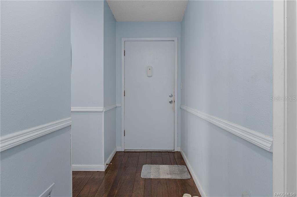 A hallway with light blue walls, white chair rail molding, and dark wood flooring — 2400 FOREST DRIVE UNIT 243, INVERNESS, FL